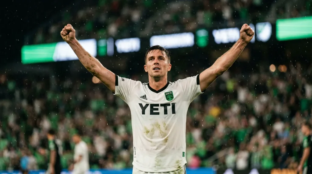 Delantero de fútbol celebrando un gol en un estadio de la MLS con aficionados al fondo